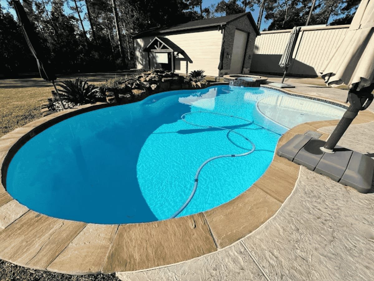 Custom gunite pool with spa and stone details in a Greater Houston backyard